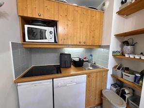 A compact kitchen with wooden cabinets, a microwave, a dishwasher, and a sink. - Cozy apartment, parking - 4 guests (Vars)