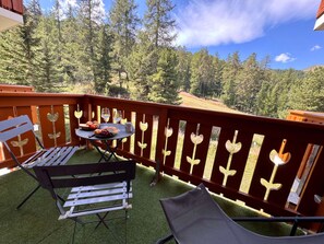 A balcony with a table set for two, a bench, and a chair. - Cozy apartment, parking - 4 guests (Vars)