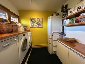 Cozinha compacta equipada com máquina de lavar, frigorífico e micro-ondas.