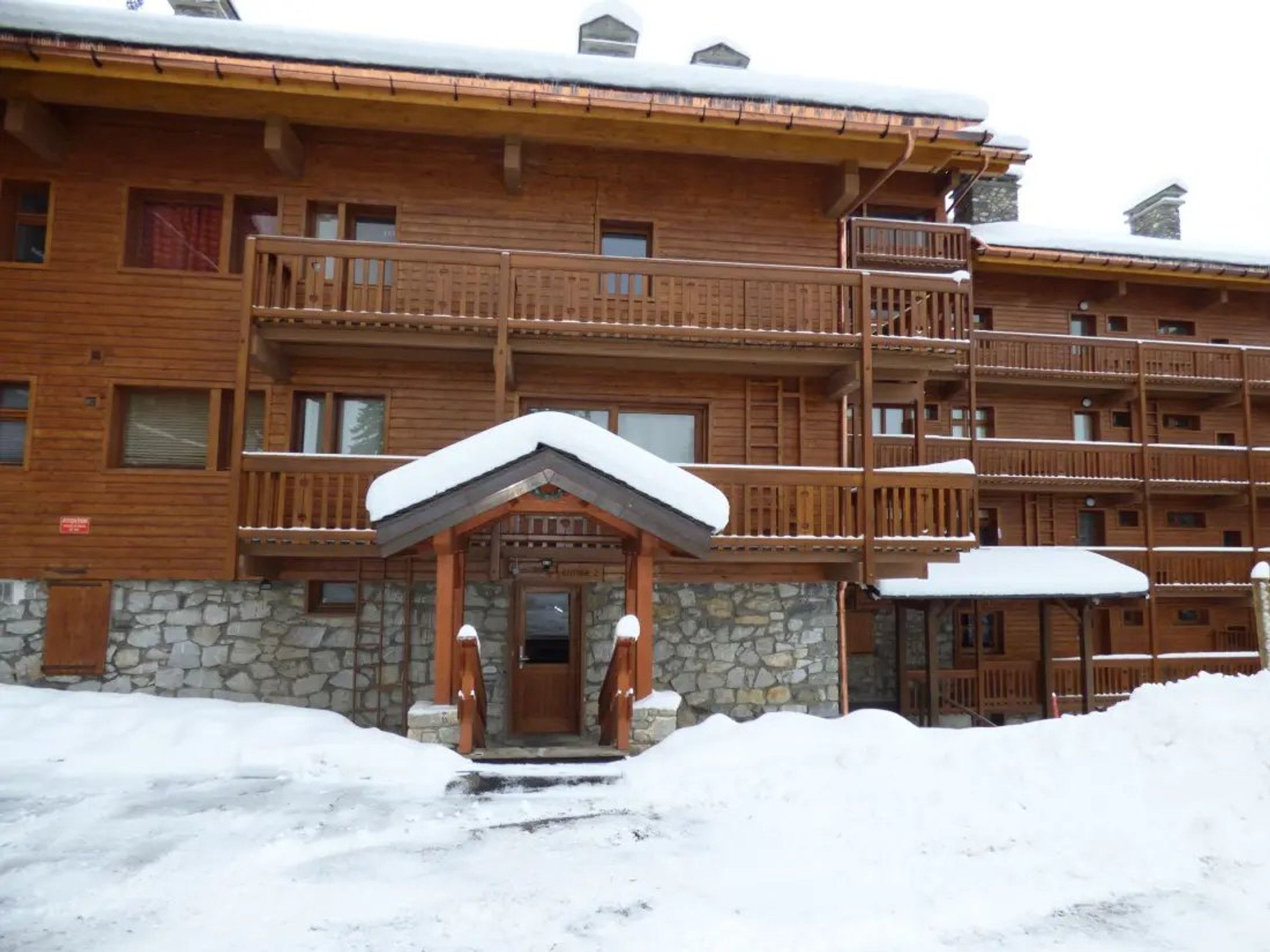A multi-story wooden building with balconies and a stone foundation.