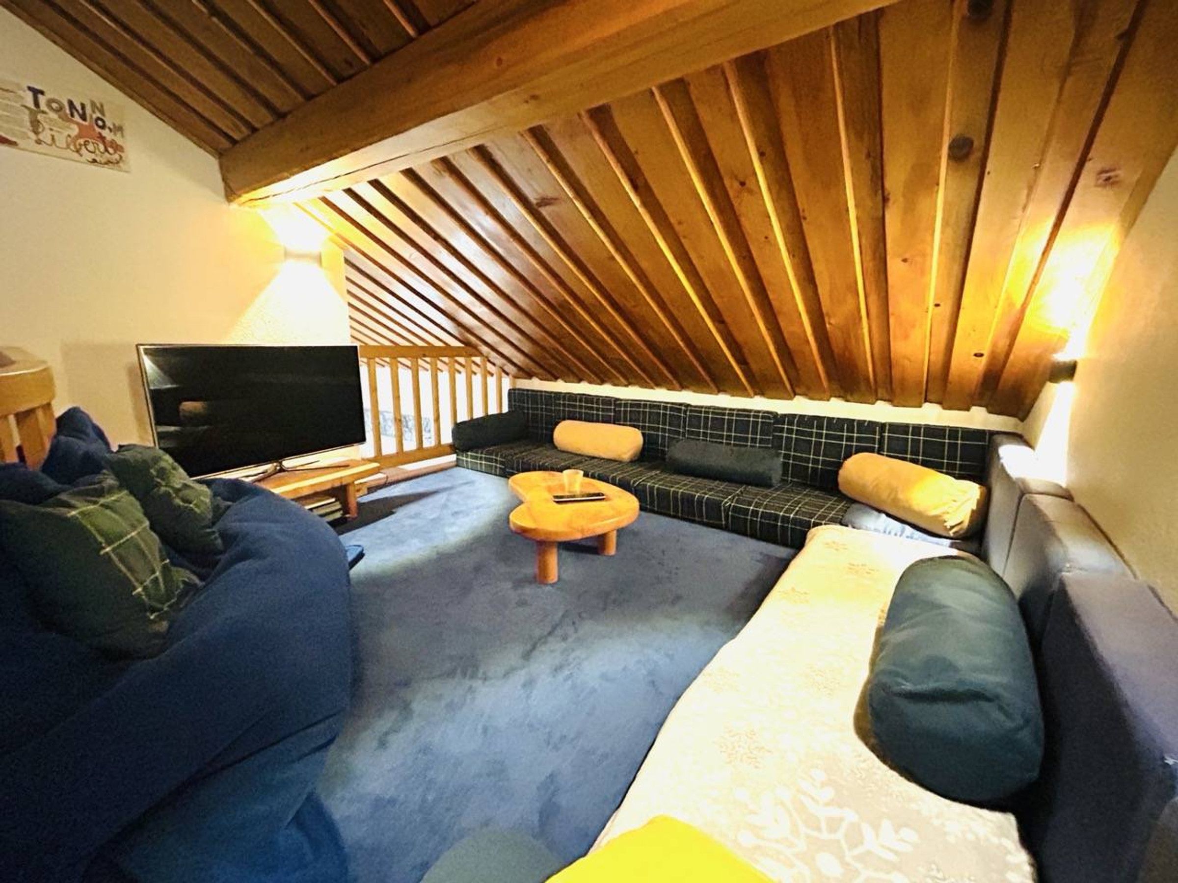 A cozy attic room with a TV, a sofa, and a small table.