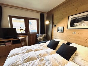 Ein Hotelzimmer mit einem Bett, einem Schreibtisch mit Fernseher und einem fensterbepflanzten Fenster.