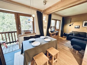 Ein gemütliches Wohnzimmer mit Essbereich, Holzböden und großen Fenstern.