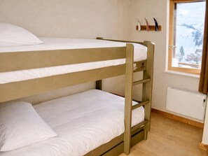 Ein Schlafzimmer mit Etagenbetten, einem Fenster und einer Heizung.