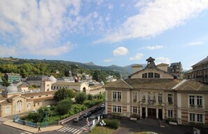 A historic building with classical architecture, a central courtyard, and a view of surrounding hills. - T3 Apartment mountain view - 5 guests (La Bourboule)