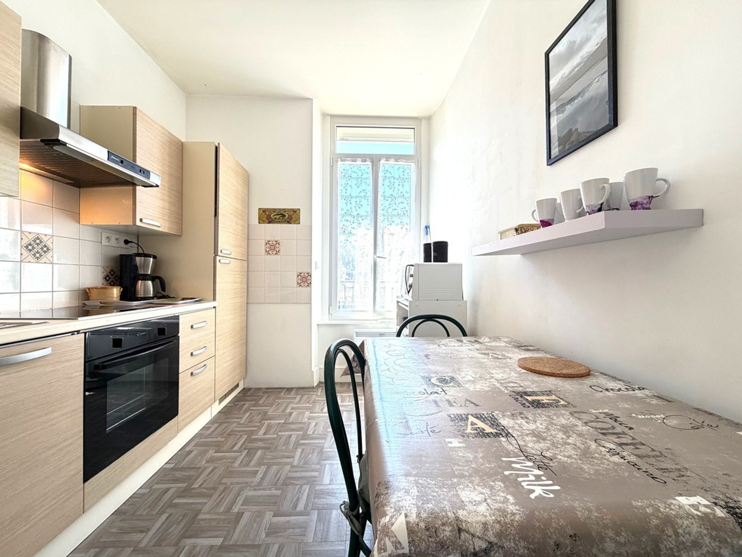 A modern kitchen with a herringbone floor pattern, a built-in oven, and a coffee maker.