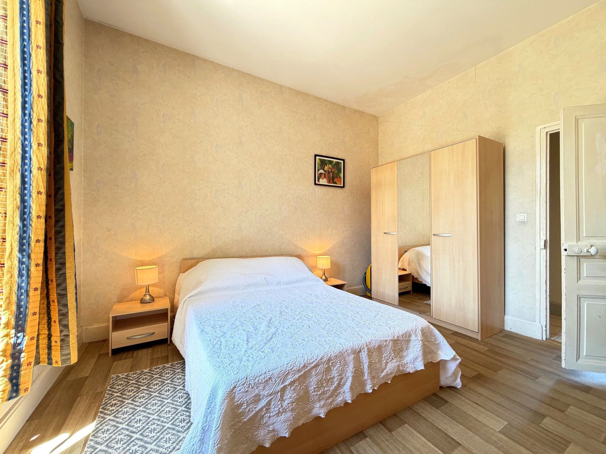 Un dormitorio con cama, lámparas de noche, un armario y un tapete estampado.