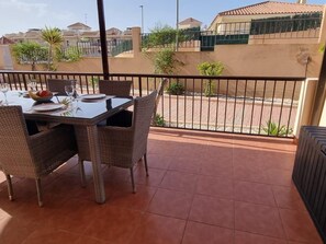 A balcony with a table set for dining, wicker chairs, and a view of the neighborhood. - Modern apartment, mountain views - 4 guests (Aguilas)