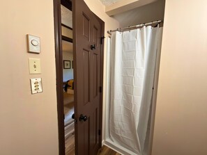 A room with a wooden door, a white shower curtain, and a light switch on the wall. - Updated 3 bedroom condo- walking distance to ski slopes! (Sugar Mountain)