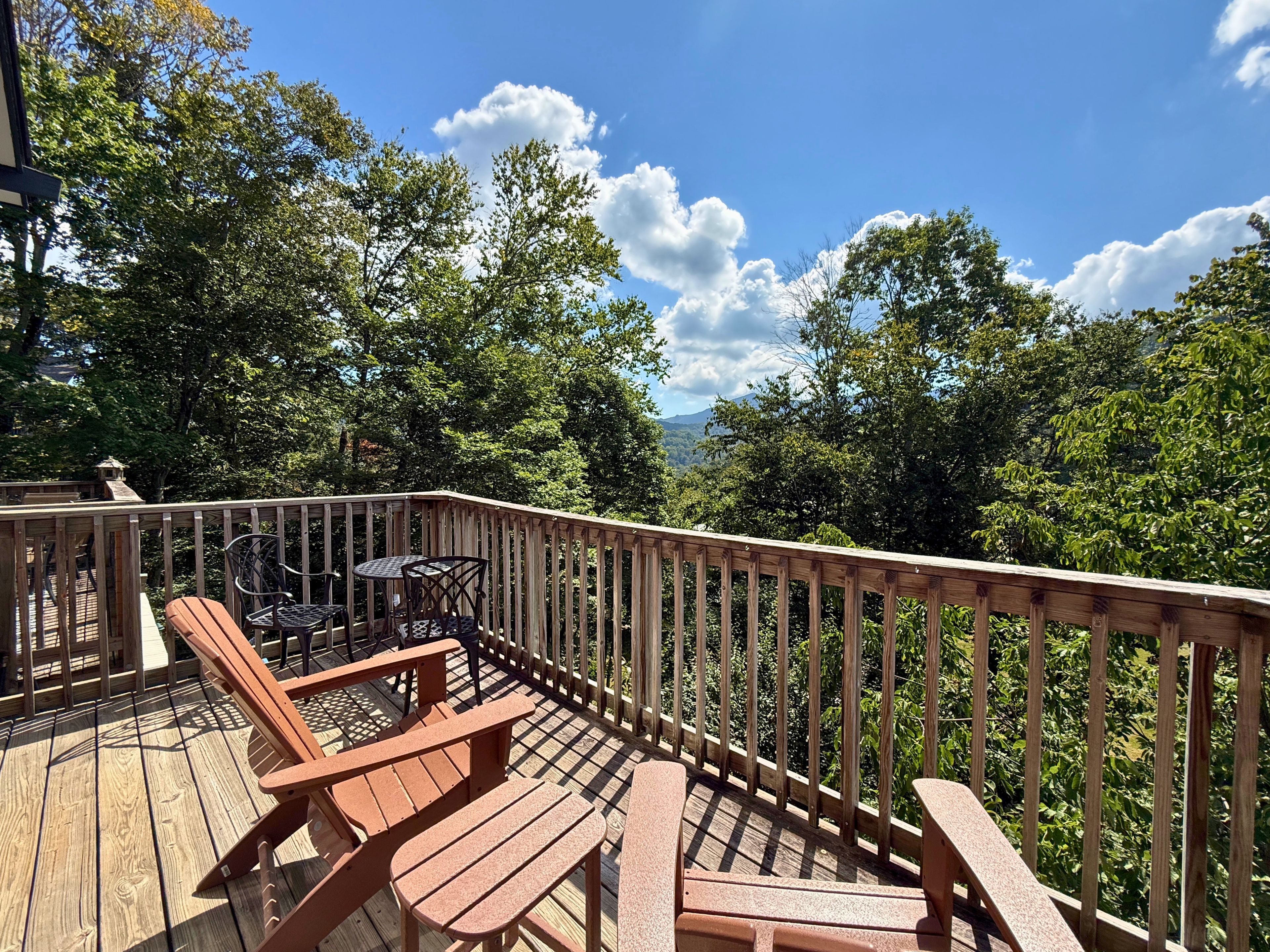 Une terrasse en bois, aménagée avec du mobilier d’extérieur, notamment des chaises et une table, et offrant une vue sur une zone boisée.