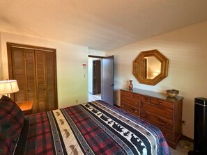 A bedroom with a bed, a dresser, a mirror, and a door. - Updated 3 bedroom condo- walking distance to ski slopes! (Sugar Mountain)
