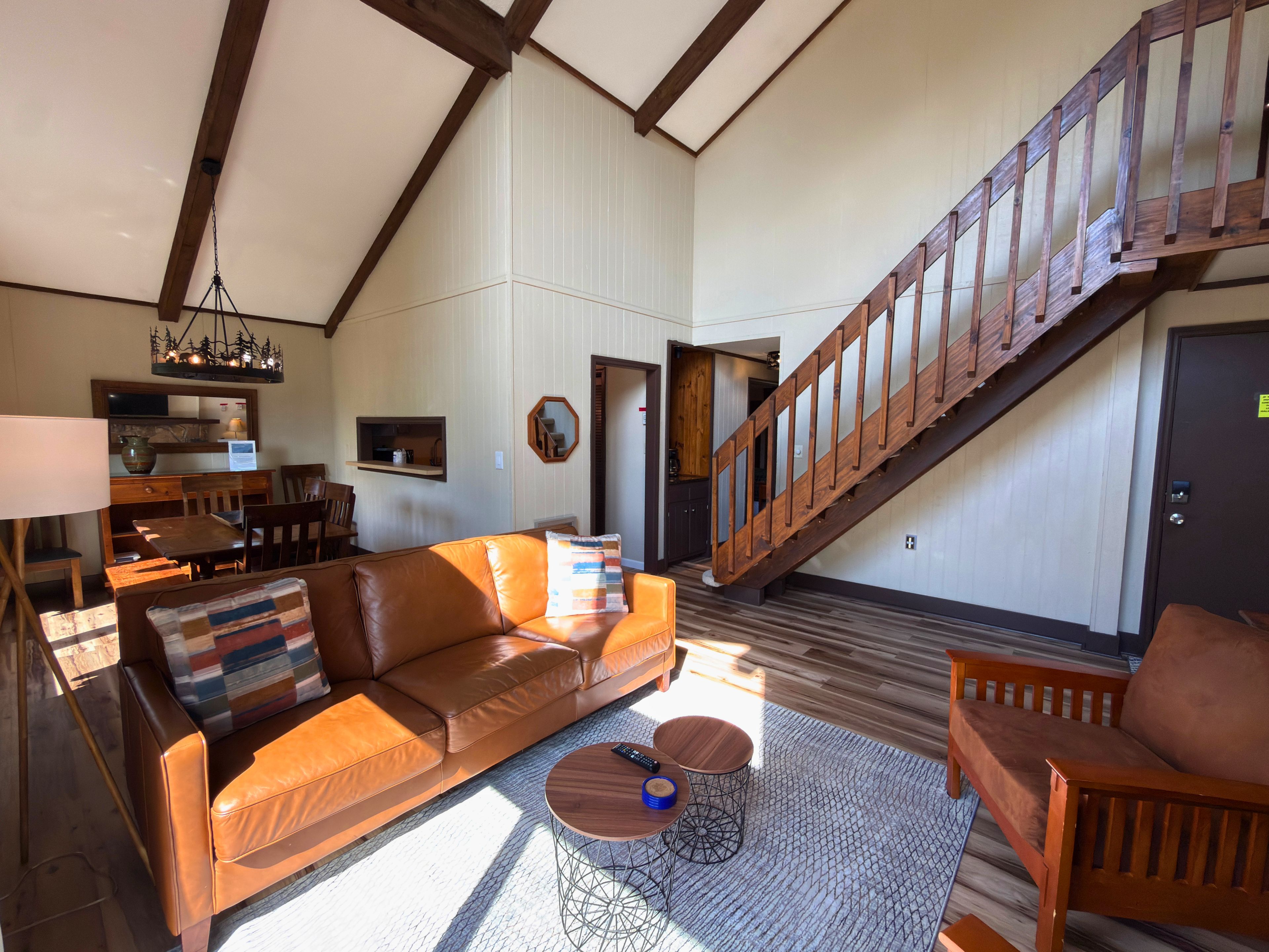 A spacious living area with a leather sofa, a coffee table, and a staircase.