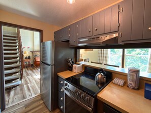 A kitchen with a stainless steel refrigerator, a stove, and wooden cabinets. - Updated 3 bedroom condo- walking distance to ski slopes! (Sugar Mountain)