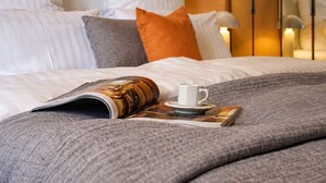 Una cama bien hecha con una revista, una taza y un libro.