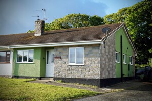 A single-story house with a green exterior, a stone facade, a chimney, and a satellite dish. - Ty Marlyn, St Davids (Haverfordwest)