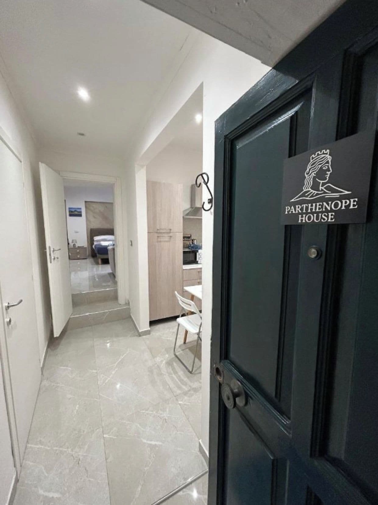 Un corridoio che porta a una stanza con un cartello che riporta la scritta 'Parthenope House'.