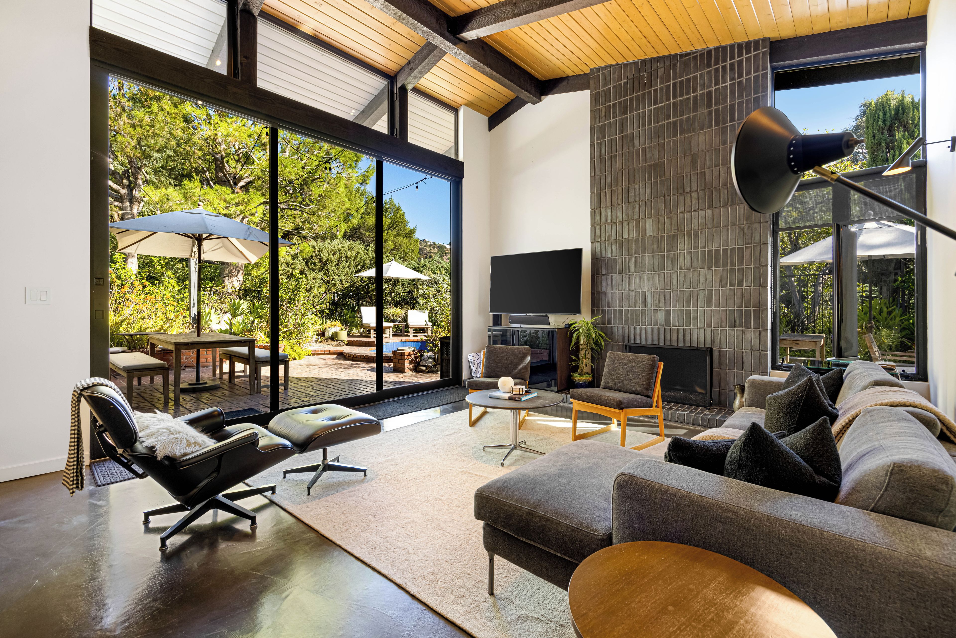 A modern living room with a fireplace, large windows, and outdoor seating.