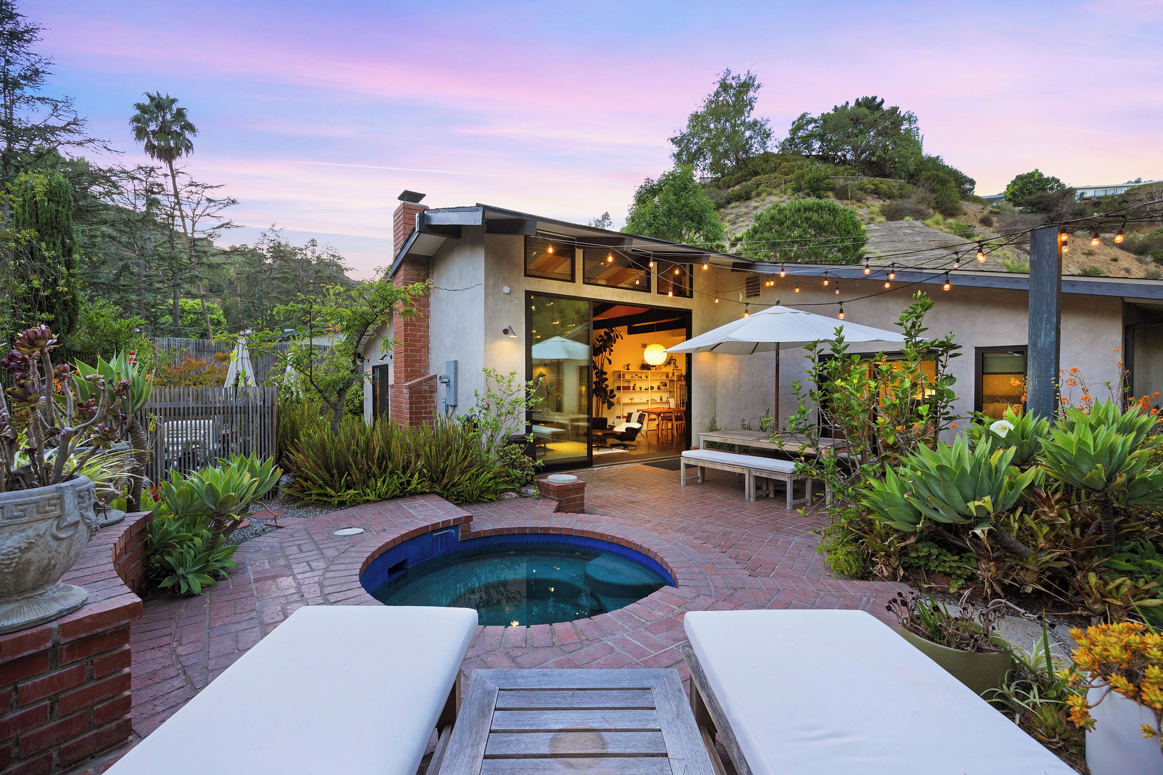 A modern house with a swimming pool, outdoor seating, and a garden.