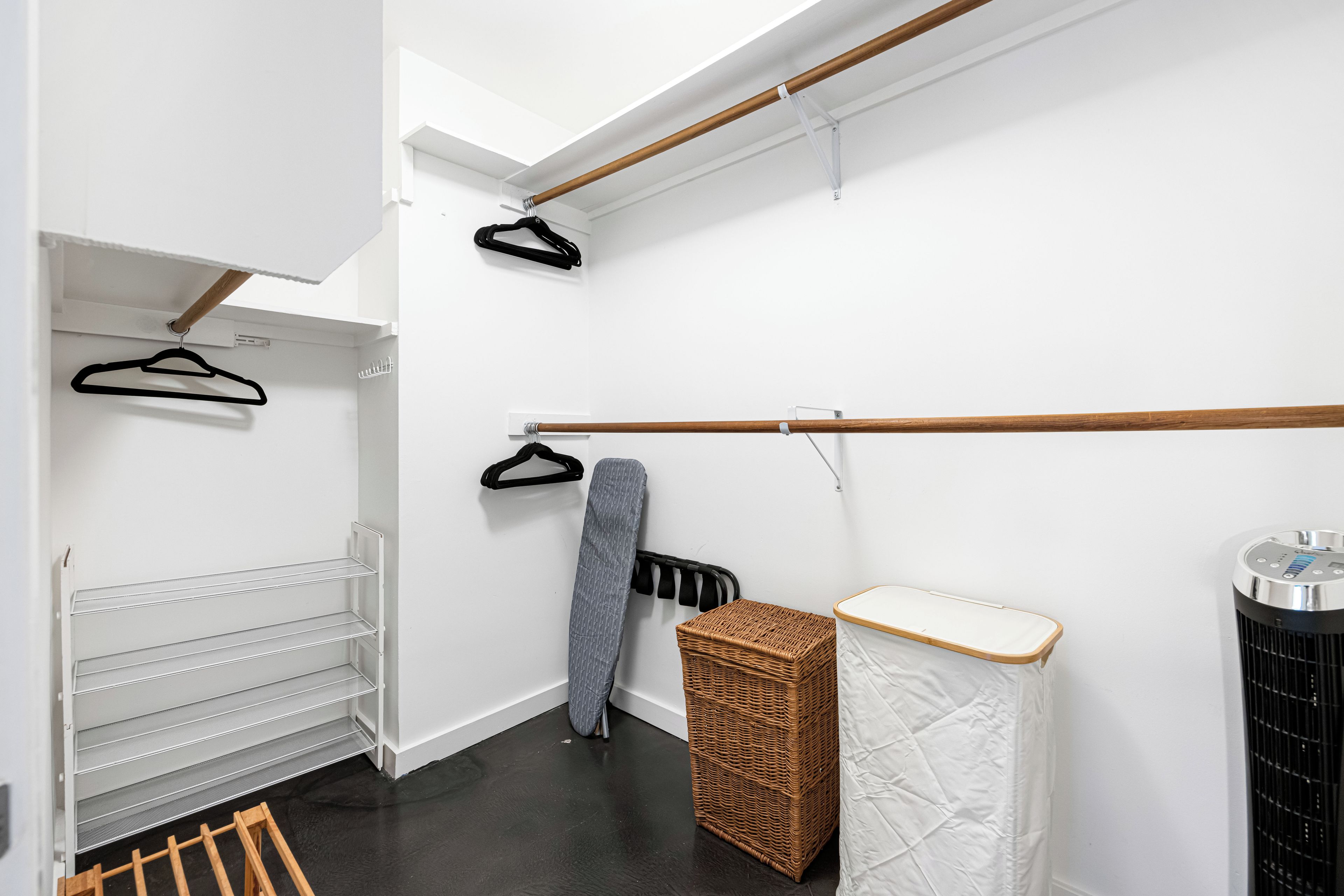 A walk-in closet with open shelving, a drying rack, and a storage bin.