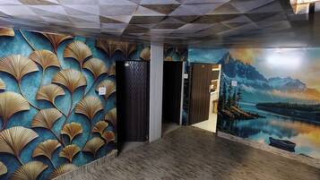 Un pasillo con un mural de montañas y un lago, piso de madera y una puerta con revestimiento texturizado.