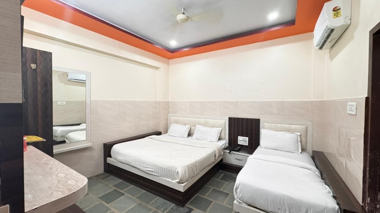 Una habitación de hotel con dos camas, una mesita de noche, un espejo y un equipo de aire acondicionado.