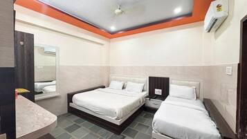 Una habitación de hotel con dos camas, una mesita de noche, un espejo y un equipo de aire acondicionado.