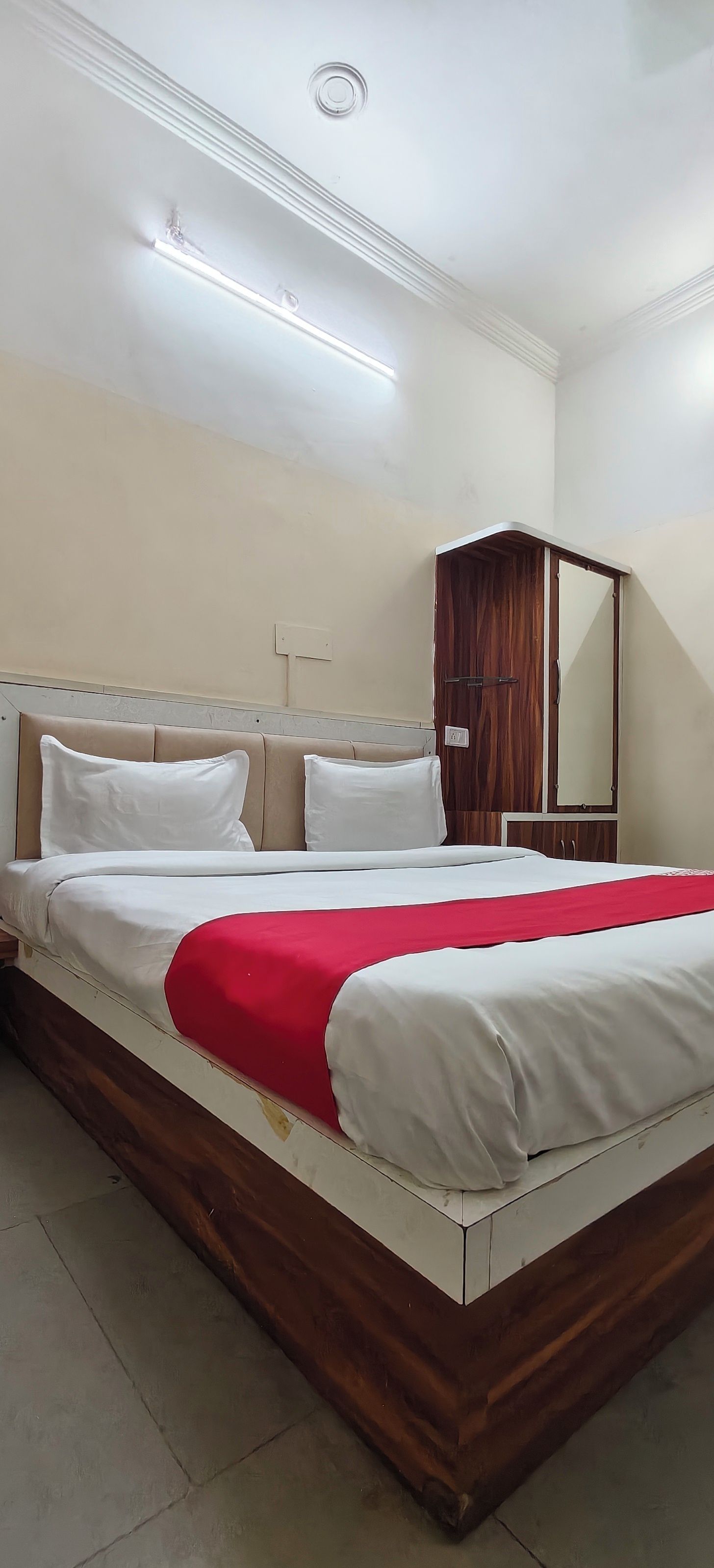 A standard hotel room with a bed, a wardrobe, and a mirror.