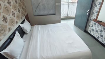 A hotel room with a bed, a window, and patterned wallpaper.