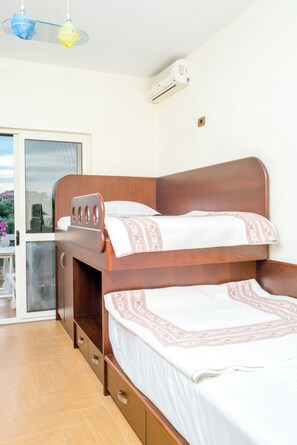 A bedroom with a bunk bed, a small desk, and a sliding glass door leading to an outdoor area.