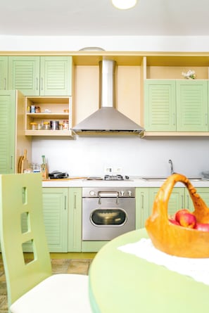 A kitchen with green cabinets, a stainless steel range hood, and a stove.