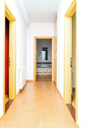 A narrow hallway leading to a bedroom with a bed, a radiator, and a window with blinds. - Twin Villa 1 Tragjas,  Nature & River near Vlora (Tragjas)