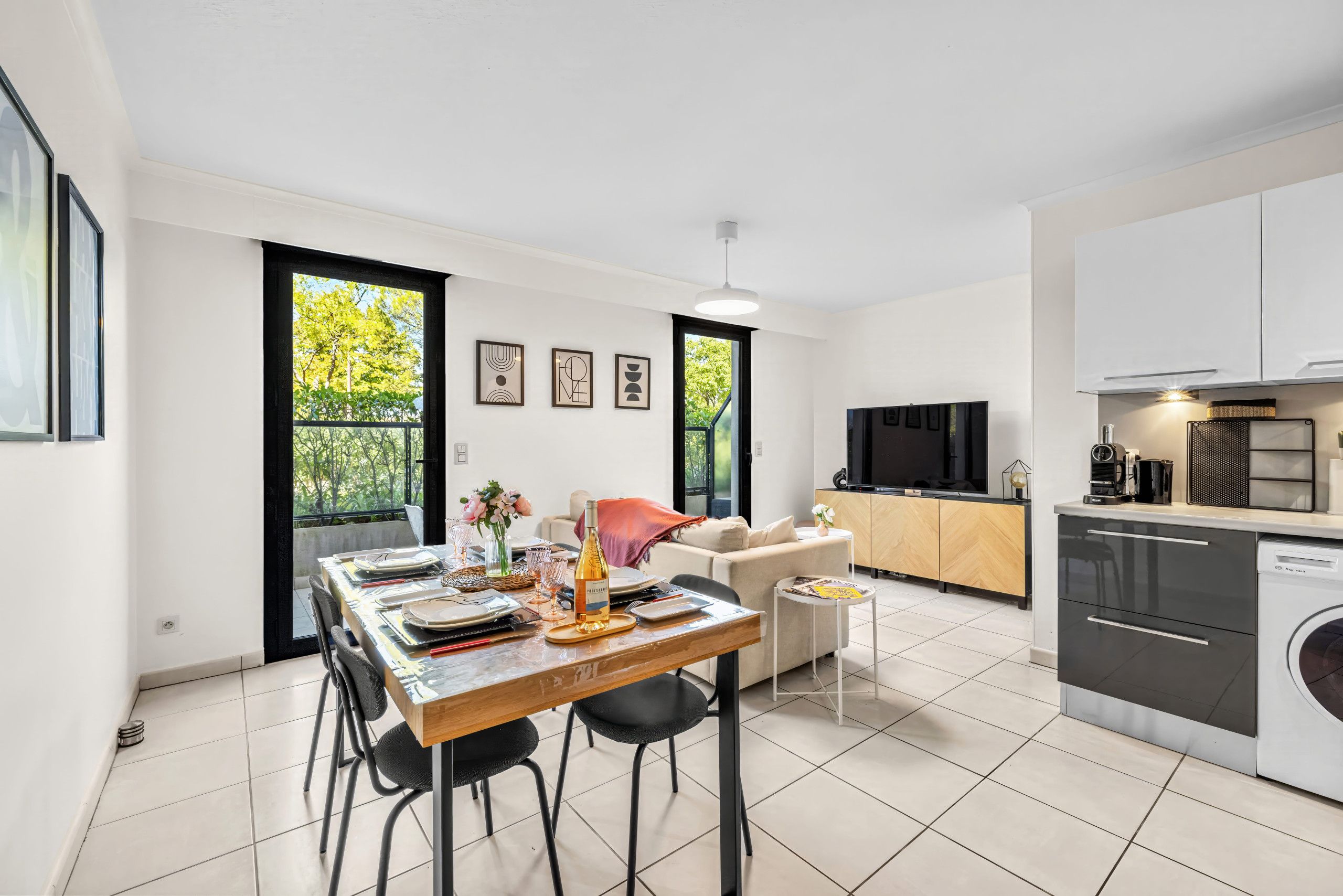 Una cocina moderna con horno empotrado, comedor con mesa para dos personas y sala de estar con sofá.