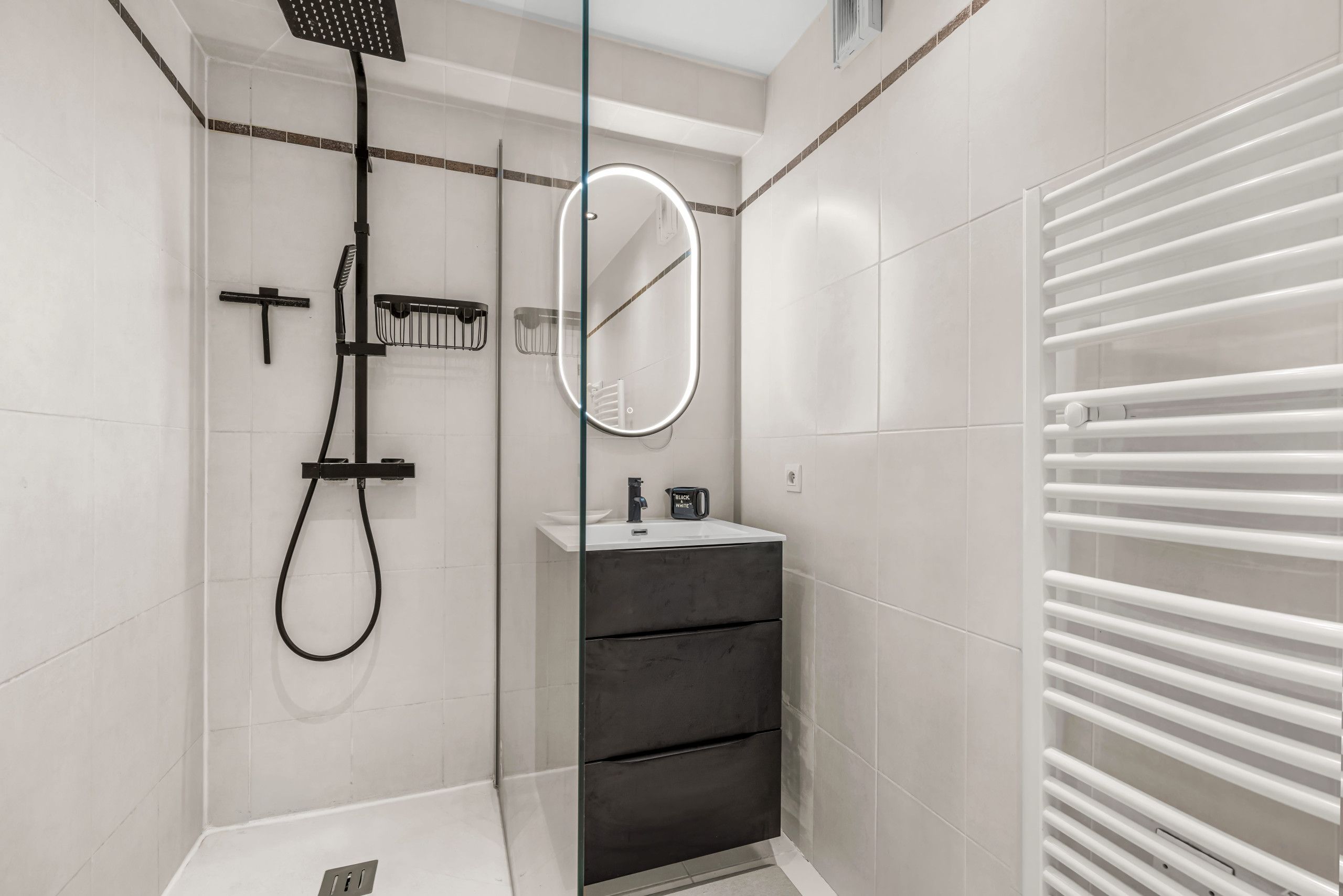 A modern bathroom with a shower, a mirror, and a towel rack.