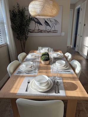 A dining area with a wooden table set for six, surrounded by white chairs. - The Golden Gator - Waterfront, Heated Pool, Lanai, Golf & Near Gulf Beaches (Rotonda West)