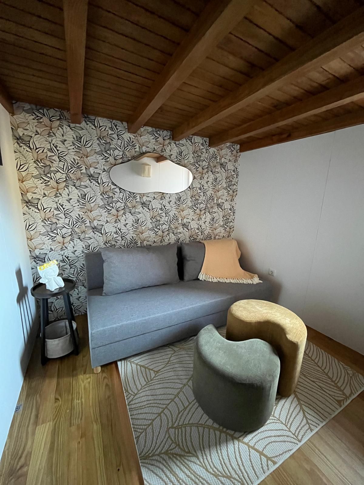 Une pièce chaleureuse avec un canapé gris, une petite table ronde et un tapis à motifs.
