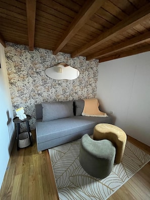 A cozy room with a grey sofa, a small round table, and a patterned rug. - Ant House (Ponte da Barca)