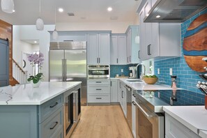 Une cuisine moderne dotée d’appareils électroménagers en acier inoxydable, de meubles de couleur bleu clair et d’un dosseret de crédence recouvert de carreaux bleus.