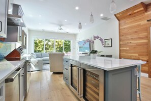 A modern kitchen with a large island, built-in appliances, and a view of a garden through large windows. - ISLA BLUE ~ NEW LISTING! Stunning 4 BR/4.5 Ba Home w/ Pool and Parking! (Key West)