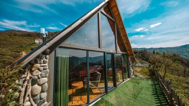 A modern house with a sloped roof, large glass windows, and a stone exterior.