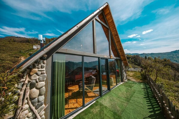 A modern house with a sloped roof, large glass windows, and a stone exterior.