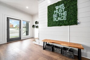 A modern interior with a bench, a wall-mounted sign, and a door leading outside. - Walk to Hattie B s - East Nashville Sleeps 12 (Nashville)