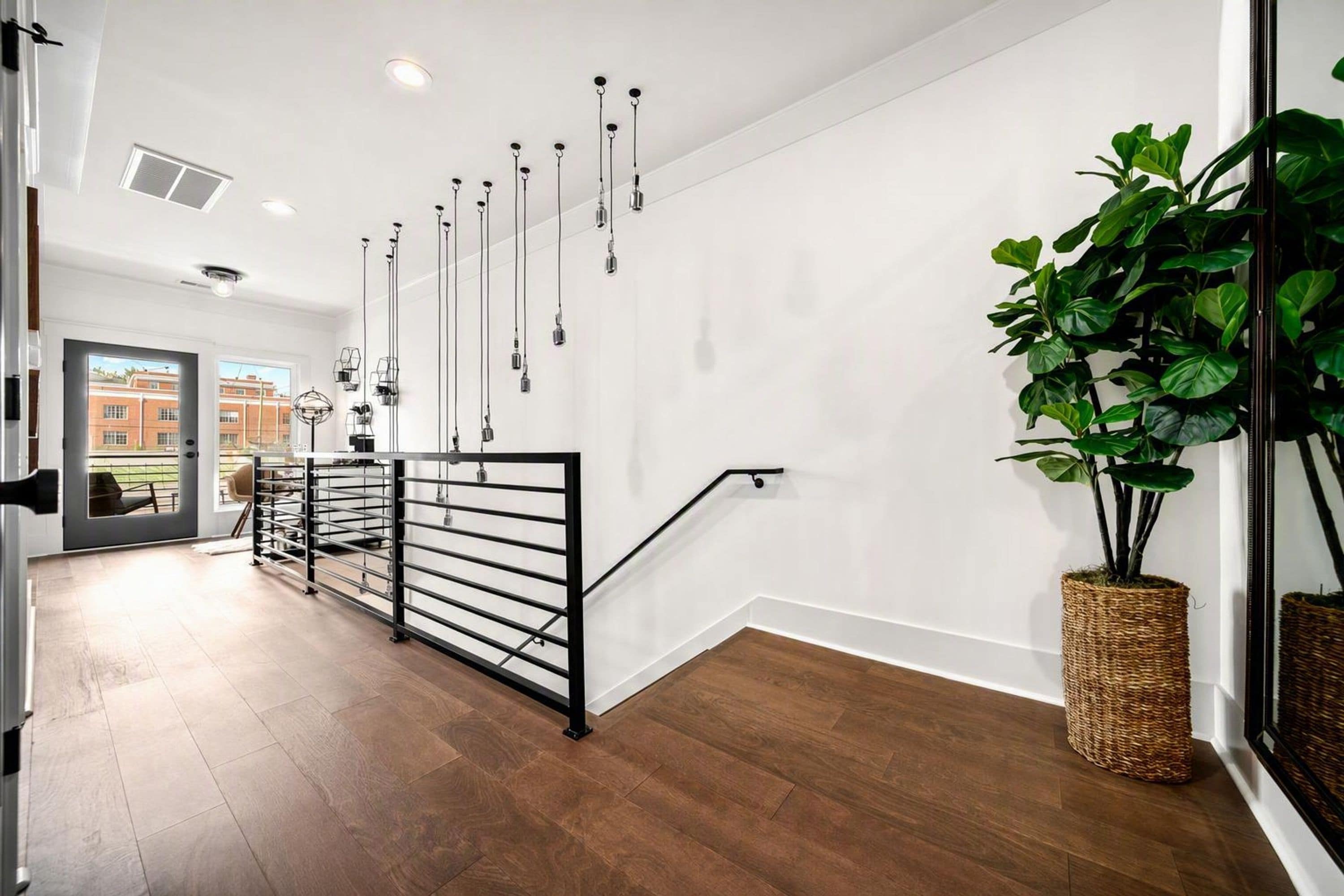 Un intérieur moderne avec un escalier, une vue sur l’extérieur et une grande plante verte.