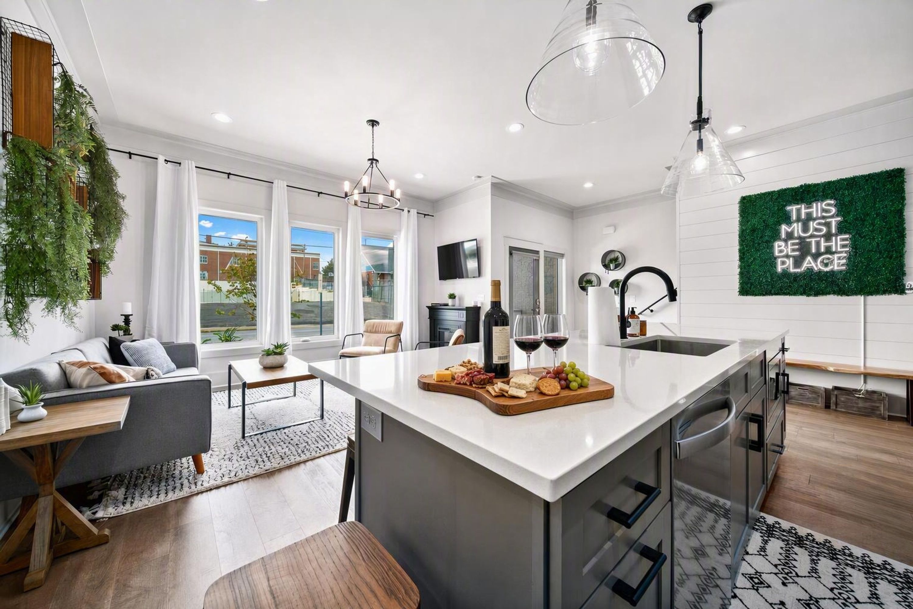 A modern kitchen with a central island, large windows, and a view of the outside.