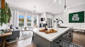 A modern kitchen with a central island, large windows, and a view of the outside.