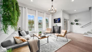 A modern living room with a sofa, armchairs, a coffee table, and a fireplace.
