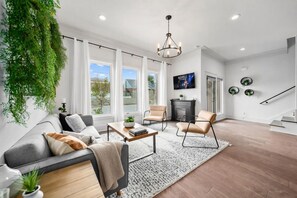 Uma sala de estar moderna com um sofá, poltronas, uma mesa de centro e uma lareira.
