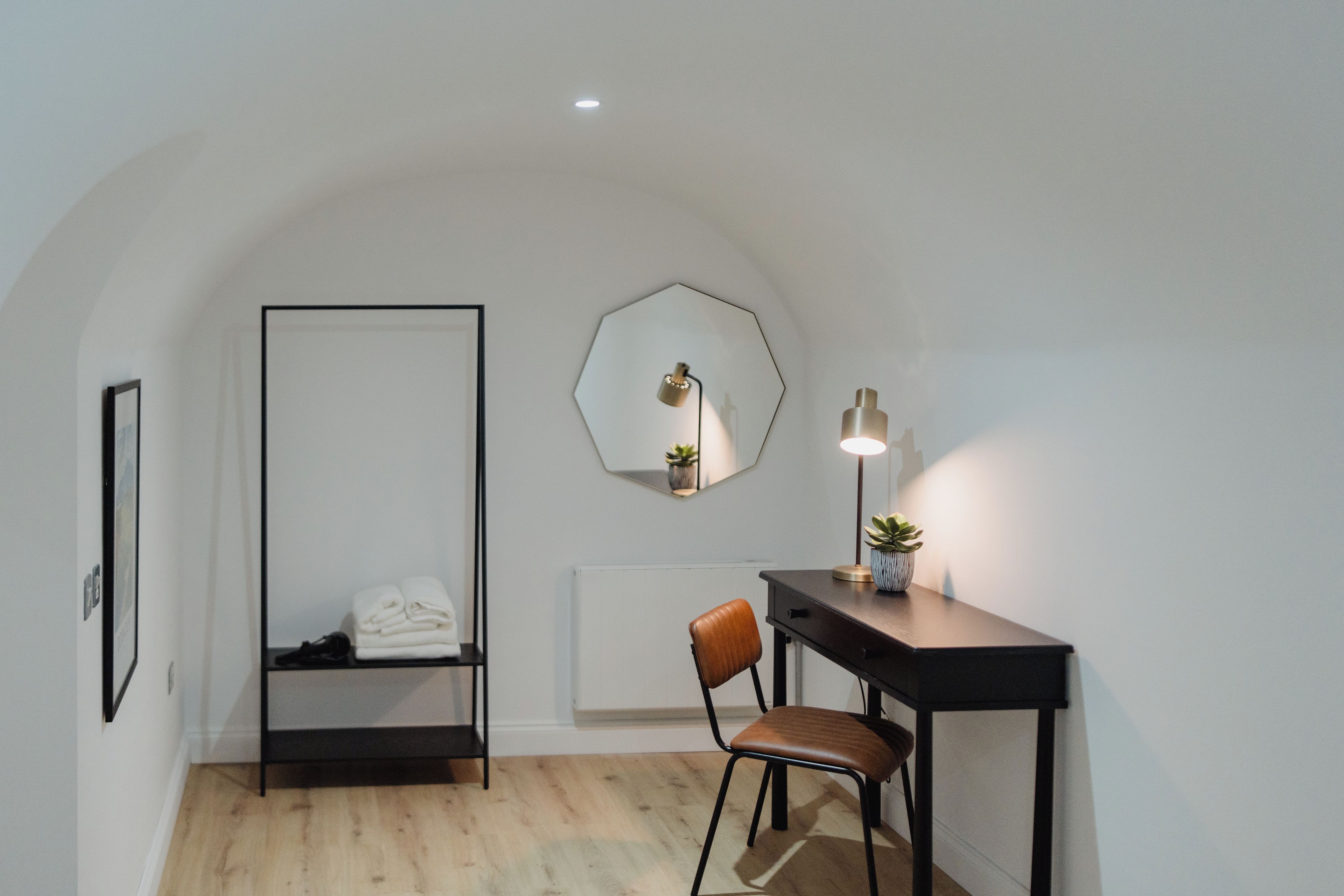 A room with a desk, chair, and a hanging light fixture.