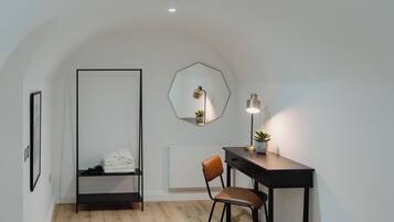 A room with a desk, chair, and a hanging light fixture.