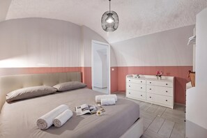 Ett modernt sovrum med en säng, sängbord, en byrå och en hängande lampa.