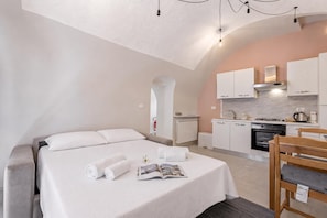 A modern hotel room with a large bed, a small kitchenette, and a dining area. - Icardi 2 Casa Di Mattoni (Dolceacqua)